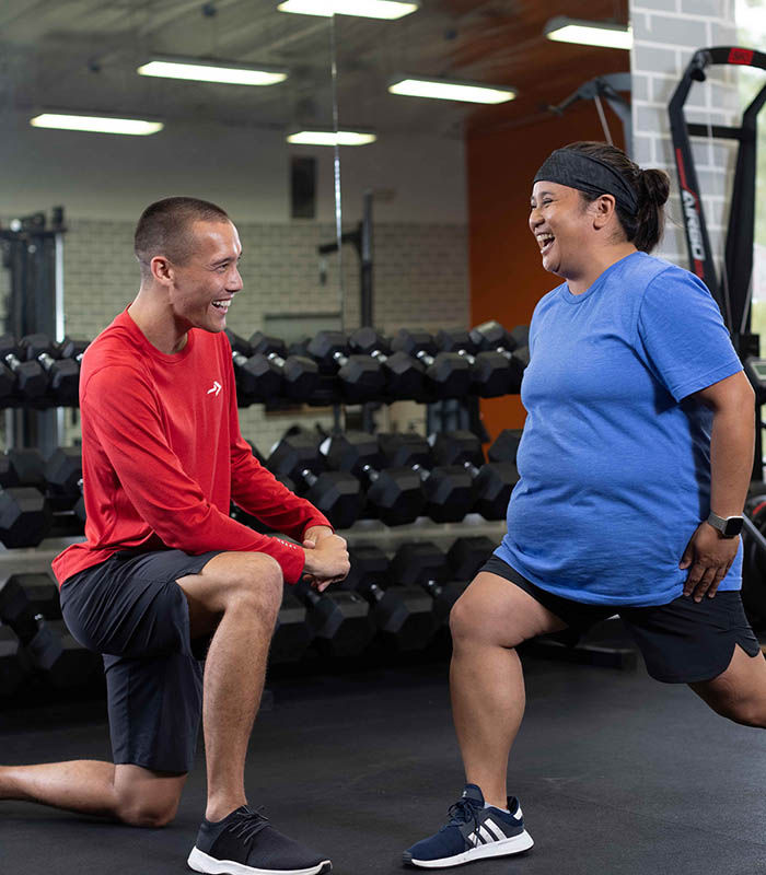 ACE Size Inclusive Fitness Specialist coaching a client through a lunge exercise in a gym