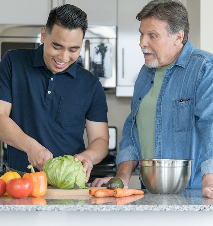 ACE Fitness Nutrition Specialist teaching a client about healthy eating while preparing vegetables in the kitchen